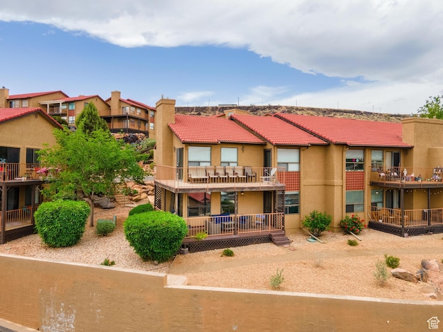 back of property featuring stucco siding, a residential view, a chimney, and a tiled roof