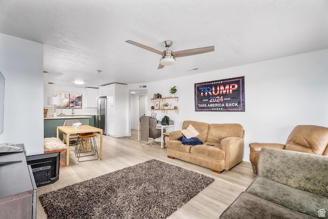 living area with a ceiling fan and light wood finished floors