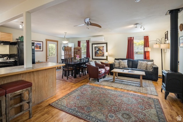 168 S 100 W, Moab, UT 84532 - living area with light wood-style flooring, a healthy amount of sunlight, a wood stove, and a wall mounted air conditioner