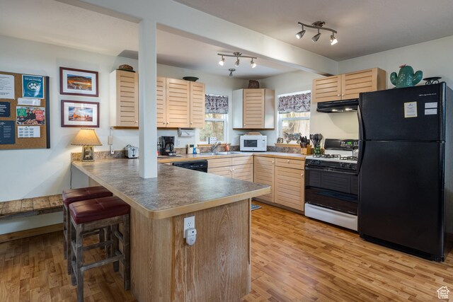 168 S 100 W, Moab, UT 84532 - kitchen with light brown cabinetry, a sink, freestanding refrigerator, gas range, and a peninsula