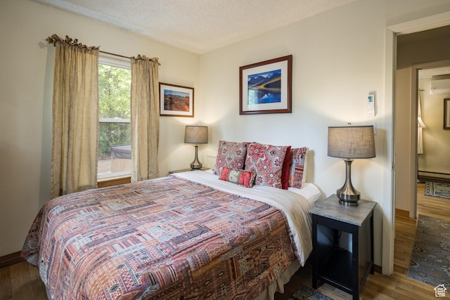 168 S 100 W, Moab, UT 84532 - bedroom featuring a textured ceiling, baseboards, a wall mounted air conditioner, baseboard heating, and wood finished floors