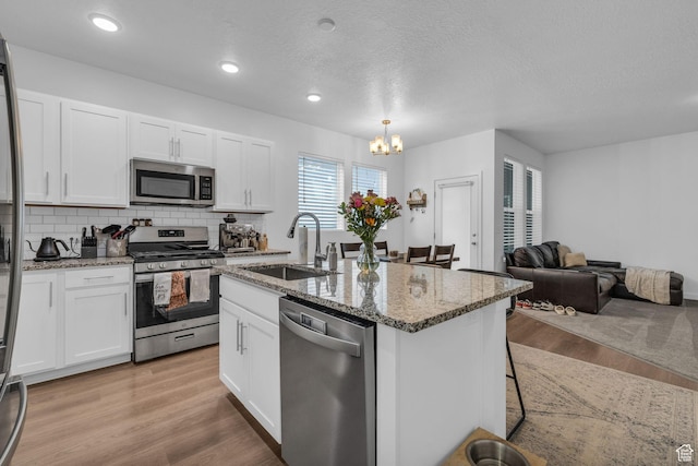 1578 W Andover Rd S, South Jordan, UT 84095 - kitchen with stainless steel appliances, a sink, a notable chandelier, and light stone counters