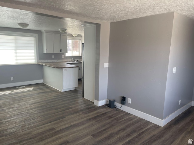 235 W 200 S, Vernal, UT 84078 - kitchen with a sink, dark wood-type flooring, baseboards, a peninsula, and a textured ceiling