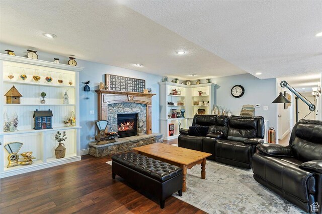 living area with recessed lighting, a textured ceiling, a stone fireplace, and hardwood / wood-style flooring