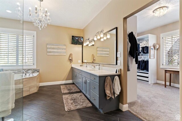 bathroom featuring double vanity, wood finished floors, a sink, baseboards, and a chandelier