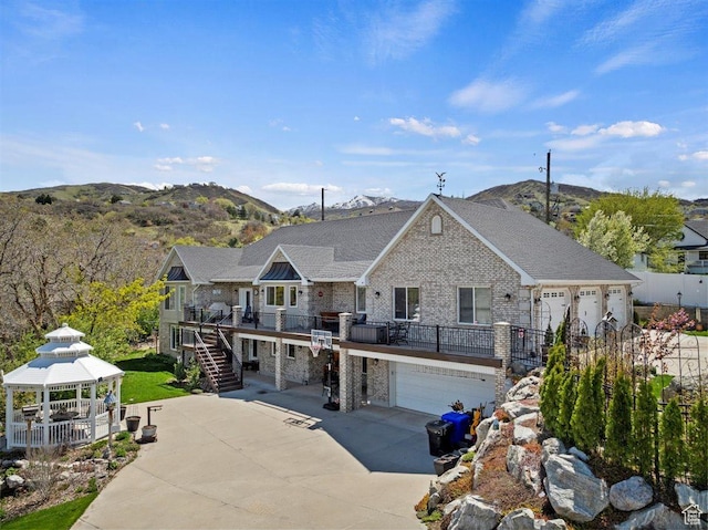 view of front facade with stairs, a gazebo, an attached garage, a deck with mountain view, and concrete driveway