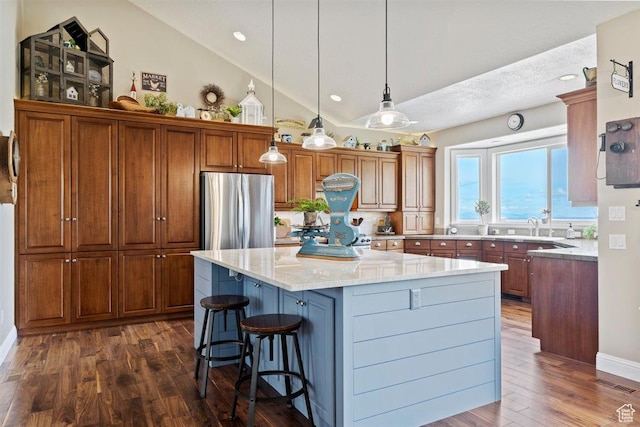 kitchen with decorative backsplash, a center island, dark wood finished floors, freestanding refrigerator, and lofted ceiling