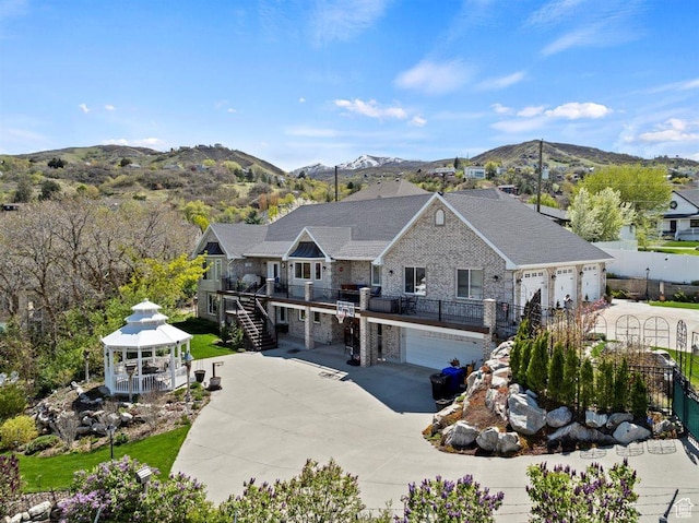 view of front of house featuring a gazebo, stone siding, stairway, a mountain view, and concrete driveway