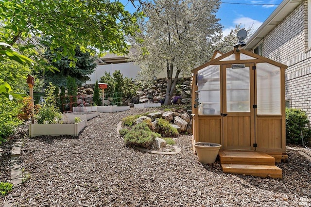 view of yard featuring an outdoor structure, an exterior structure, a vegetable garden, and fence private yard