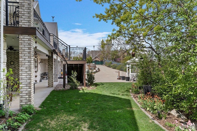 view of yard featuring a patio, ceiling fan, and stairs
