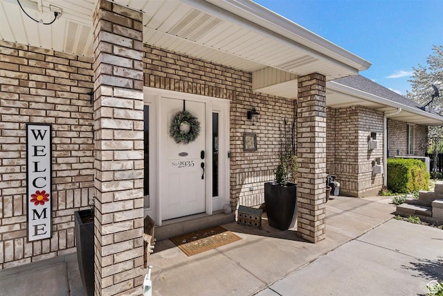 doorway to property featuring brick siding and covered porch