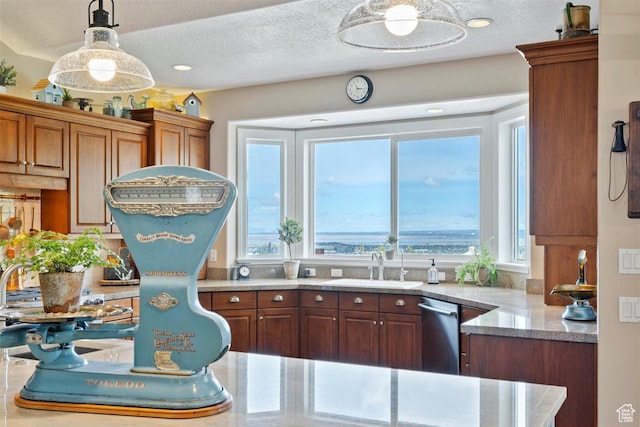 kitchen featuring hanging light fixtures, a sink, light countertops, brown cabinetry, and stainless steel dishwasher