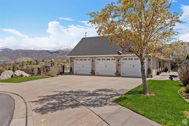 view of front of house with driveway, brick siding, a mountain view, a front lawn, and an attached garage