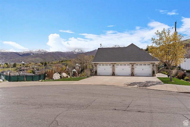 view of front of house featuring concrete driveway, fence, a mountain view, and a garage