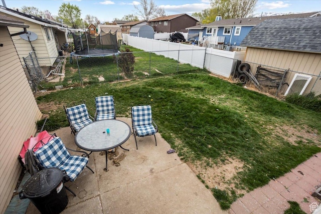 view of yard featuring a fenced backyard, a residential view, a patio, and a trampoline