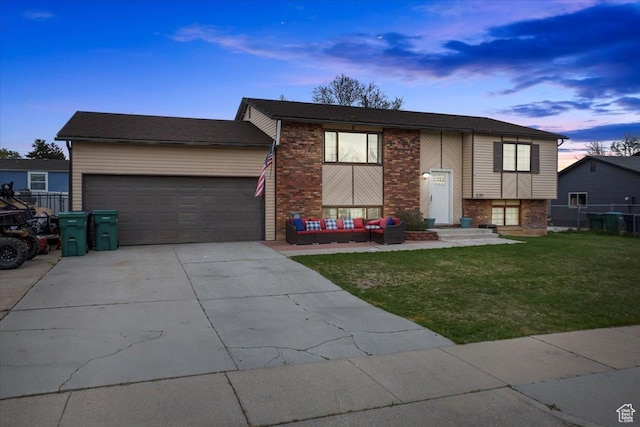 split foyer home with fence, a front lawn, concrete driveway, an attached garage, and brick siding