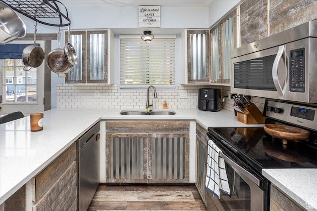 kitchen featuring plenty of natural light, decorative backsplash, stainless steel appliances, and a sink