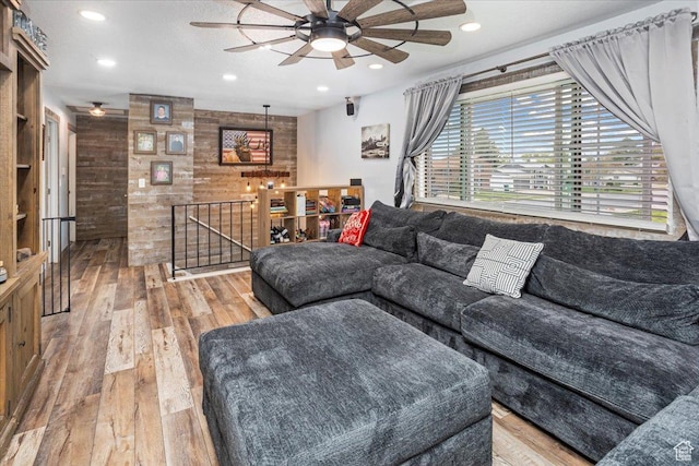 living room featuring wood-type flooring, a ceiling fan, and wood walls