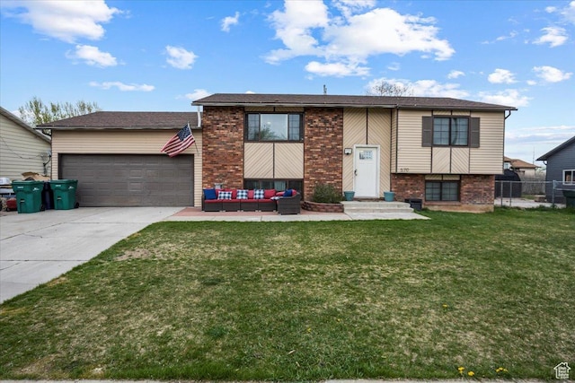 raised ranch with an outdoor living space, concrete driveway, fence, a front yard, and brick siding