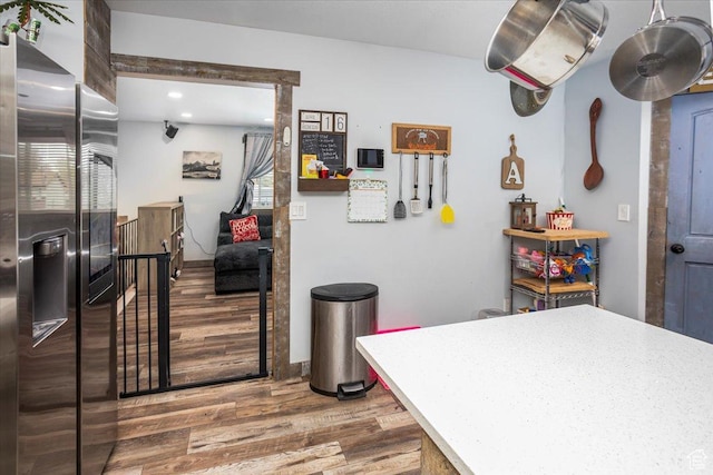 kitchen with stainless steel refrigerator with ice dispenser, light countertops, wood finished floors, and recessed lighting