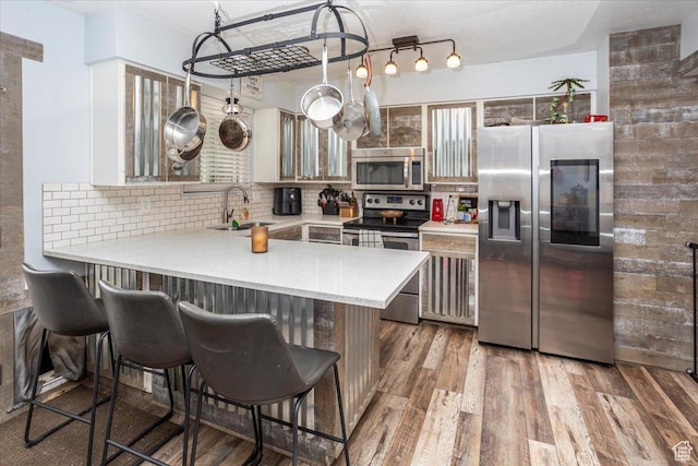 kitchen featuring decorative backsplash, appliances with stainless steel finishes, wood finished floors, and a sink