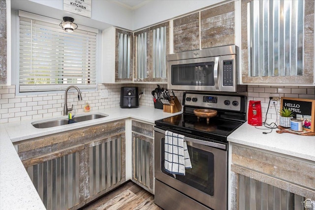 kitchen with backsplash, light wood-style flooring, stainless steel appliances, and a sink