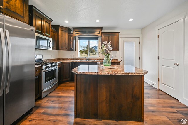 8050 W 1900 N, Petersboro, UT 84325 - kitchen with dark wood-style flooring, light stone countertops, a center island, a sink, and appliances with stainless steel finishes