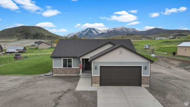 8050 W 1900 N, Petersboro, UT 84325 - view of front of house featuring a garage, a front lawn, brick siding, concrete driveway, and a mountain view