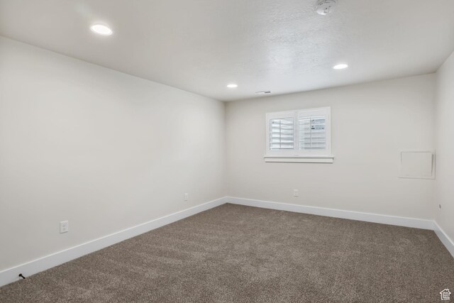 unfurnished room with dark carpet, baseboards, and recessed lighting