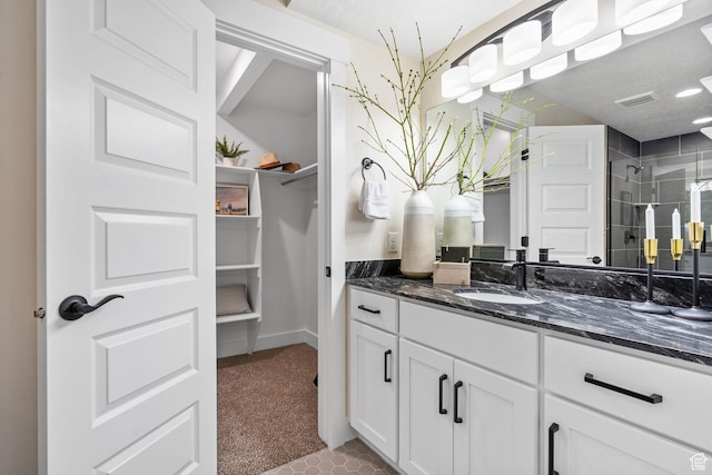 bathroom with a spacious closet, vanity, and a stall shower