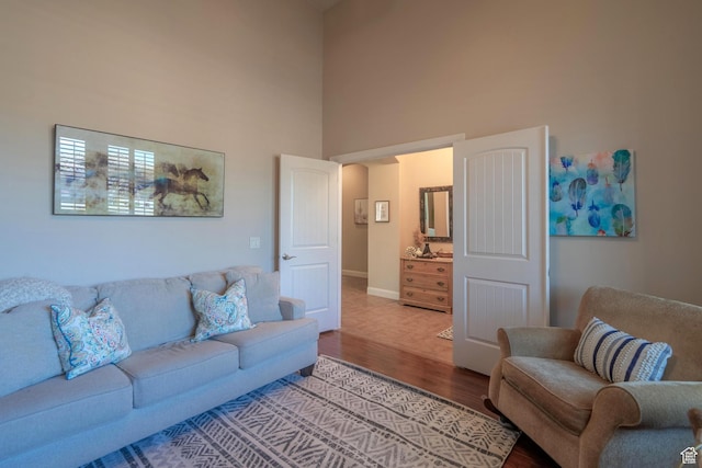 living area featuring a high ceiling, wood finished floors, and baseboards
