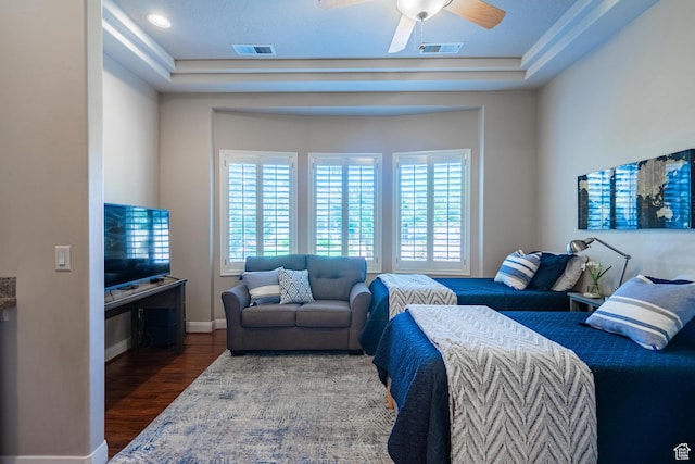 bedroom with wood finished floors, baseboards, ceiling fan, and a raised ceiling