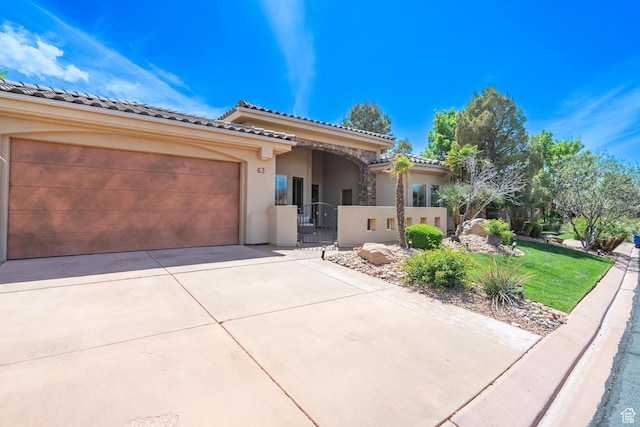 view of front facade featuring a tiled roof, driveway, stucco siding, a garage, and a gate