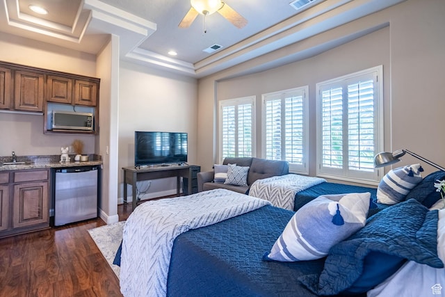 bedroom with wet bar, dark wood-type flooring, a tray ceiling, ceiling fan, and baseboards