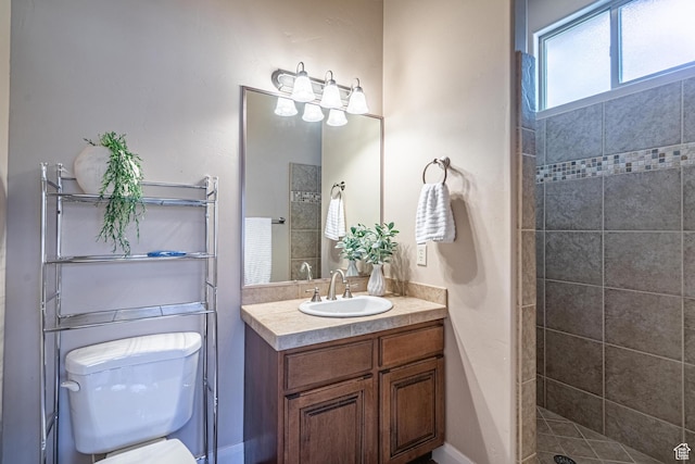bathroom with vanity, tiled shower, and toilet