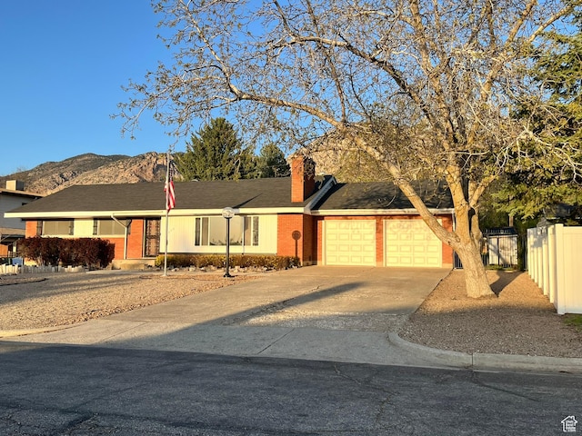 3374 Eccles E, Ogden, UT 84403 - view of front of house featuring a mountain view, concrete driveway, fence, brick siding, and an attached garage