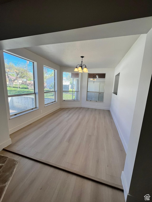3374 Eccles E, Ogden, UT 84403 - unfurnished dining area with baseboards, light wood-style floors, and a notable chandelier