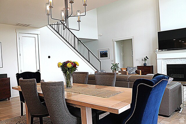 7226 Estancia Ln, Smithfield, UT 84335 - dining space with stairs, wood finished floors, a towering ceiling, a chandelier, and a glass covered fireplace