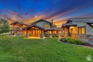 57 E 445 S, Garden City, UT 84028 - back of house at dusk featuring a lawn, stone siding, and a playground