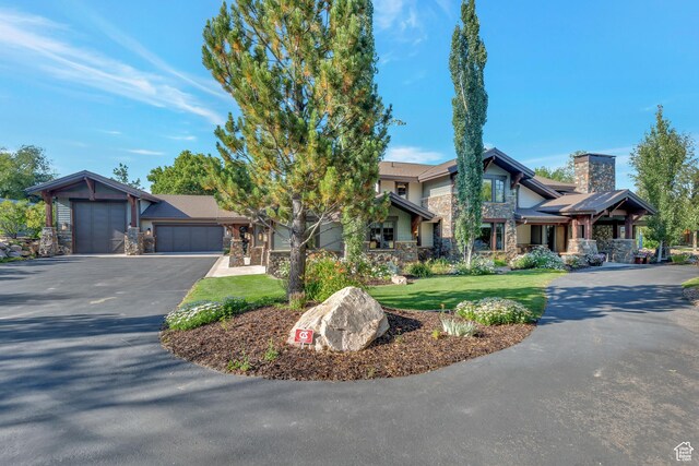57 E 445 S, Garden City, UT 84028 - view of front of home featuring driveway, stone siding, a chimney, a garage, and a front yard
