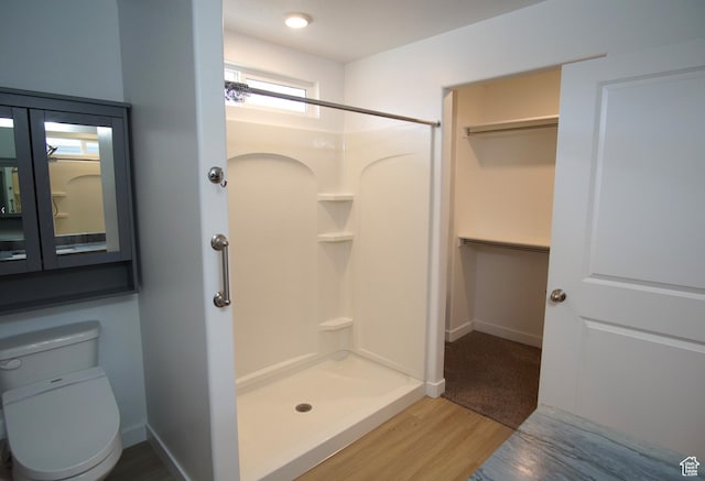 full bath with toilet, baseboards, wood finished floors, and a stall shower