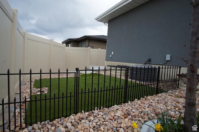 exterior space with fence, a lawn, and cooling unit