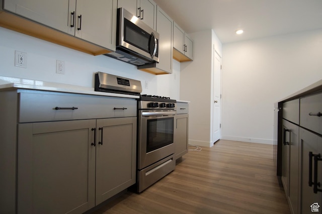 kitchen with stainless steel appliances, wood finished floors, recessed lighting, and gray cabinets