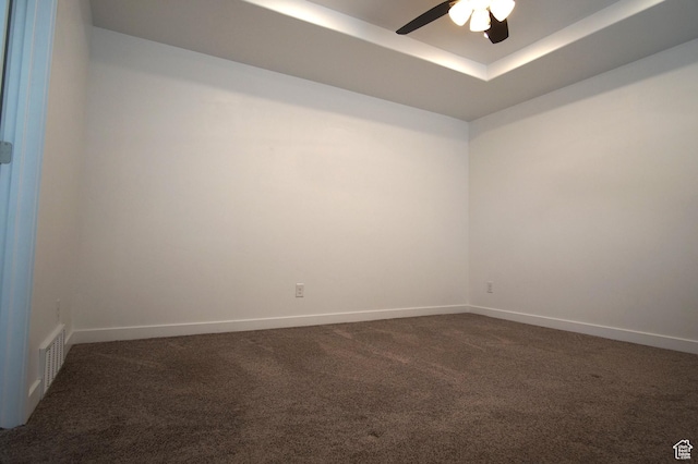 carpeted spare room with ceiling fan, baseboards, a tray ceiling, and visible vents