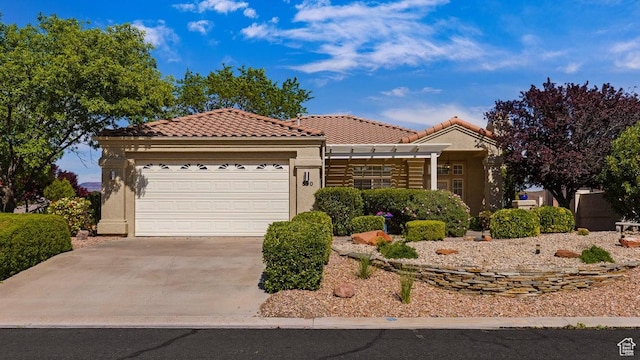 view of front of property with stucco siding, an attached garage, driveway, and a tiled roof