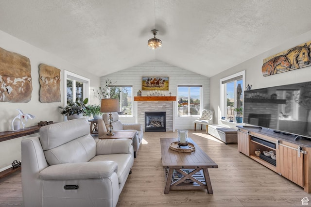 9185 S 200 W, Paradise, UT 84328 - living area with light wood-type flooring, vaulted ceiling, a fireplace, and a textured ceiling