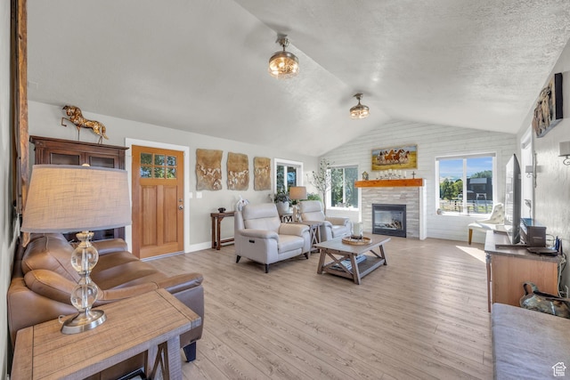 9185 S 200 W, Paradise, UT 84328 - living area featuring vaulted ceiling, a stone fireplace, a healthy amount of sunlight, and light wood-style flooring