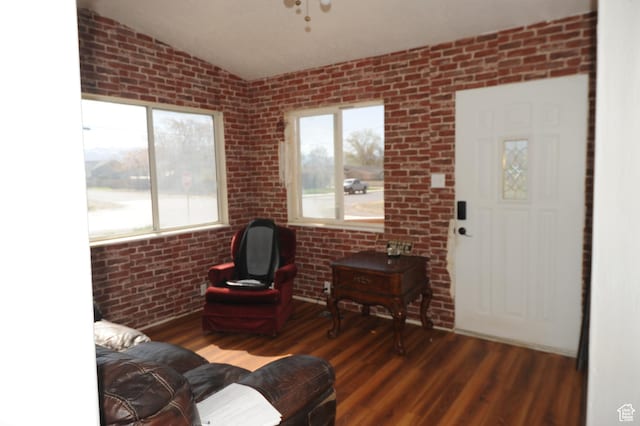 living room featuring brick wall, vaulted ceiling, and wood finished floors