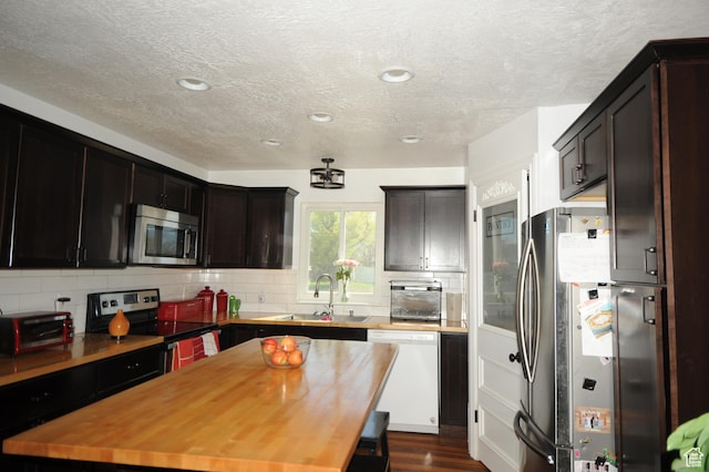 kitchen with stainless steel appliances, a sink, a textured ceiling, and tasteful backsplash