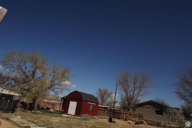 view of yard featuring a fenced backyard, a storage unit, an outdoor structure, and a trampoline